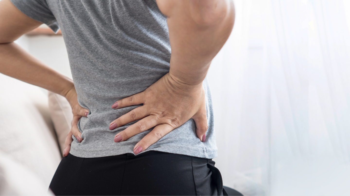 Woman holding her lower back and hip in discomfort representing menopause-related hip and lower back pain in women over 40.