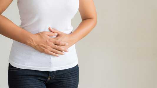 Woman holding her lower abdomen to represent menopause bloating, digestive discomfort, and belly pressure in women over 40.
